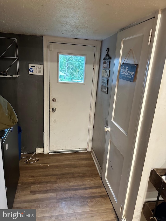 doorway to outside with a textured ceiling and dark hardwood / wood-style flooring