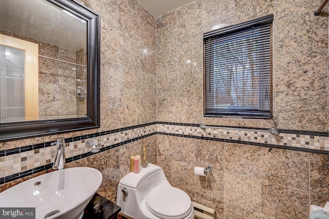 bathroom featuring a baseboard heating unit, tile walls, toilet, and sink