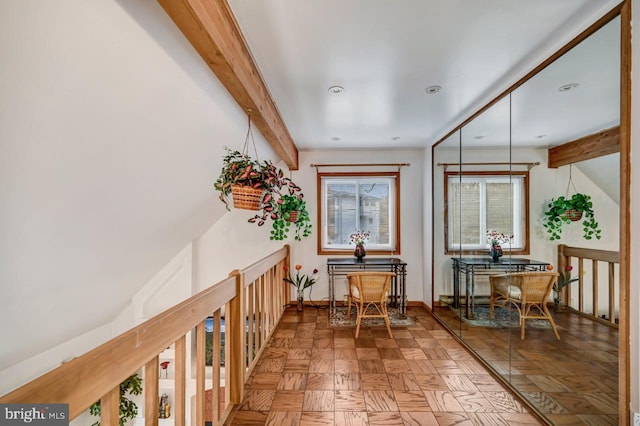 interior space with dark parquet flooring and beamed ceiling