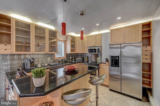 kitchen with dark stone counters, a kitchen bar, stainless steel appliances, backsplash, and hanging light fixtures