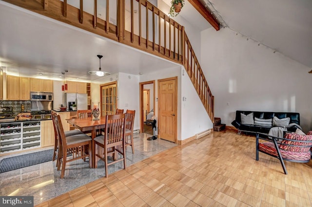 dining space with light tile floors, beam ceiling, and a towering ceiling