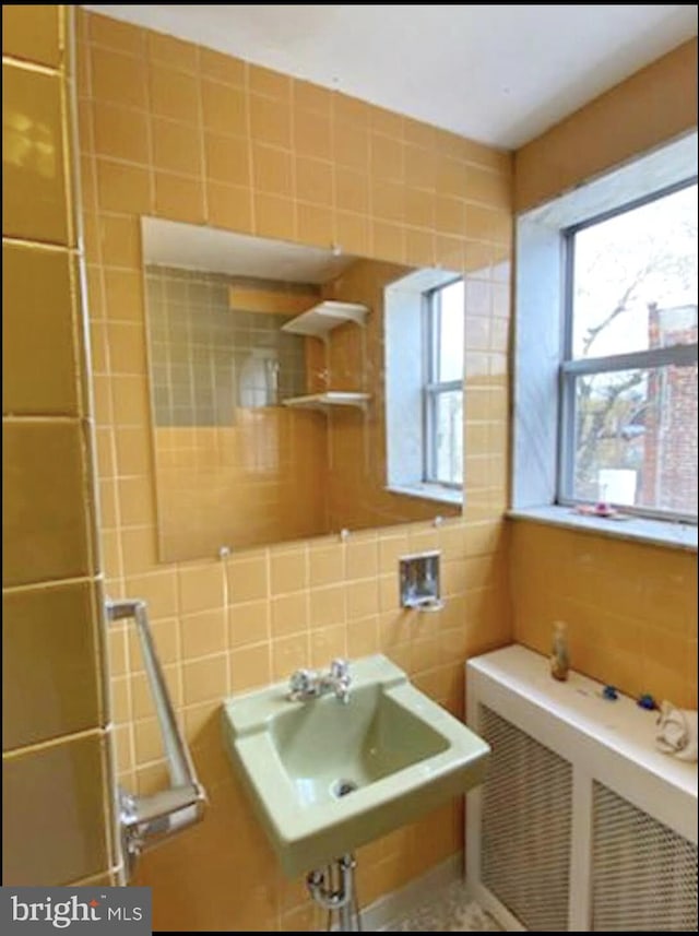 bathroom featuring radiator heating unit, tile walls, sink, and tasteful backsplash