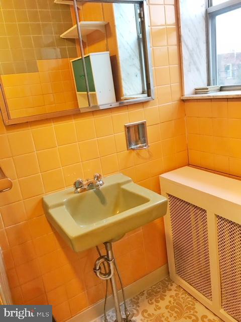 bathroom featuring tile walls, tile floors, and tasteful backsplash