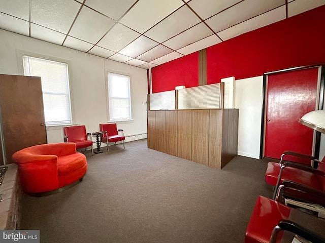 living area with dark colored carpet, a baseboard radiator, and a drop ceiling