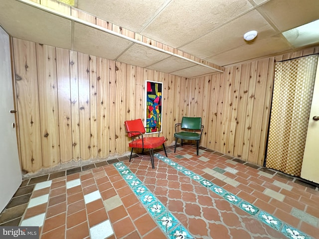 unfurnished room featuring wood walls and a paneled ceiling