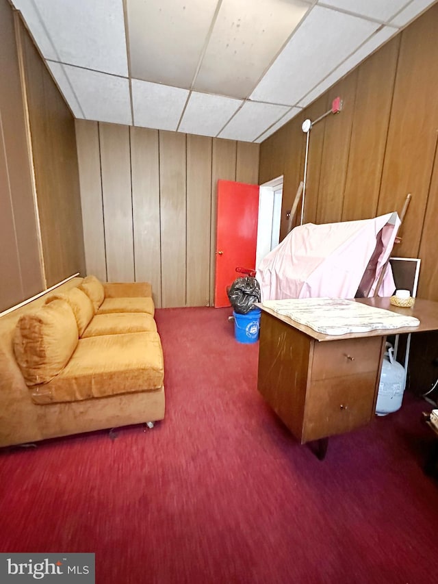 sitting room with a paneled ceiling and wooden walls