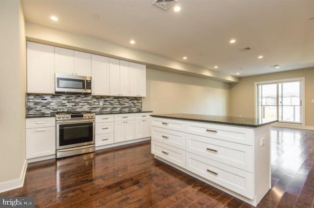 kitchen featuring white cabinets, dark wood-type flooring, backsplash, and stainless steel appliances