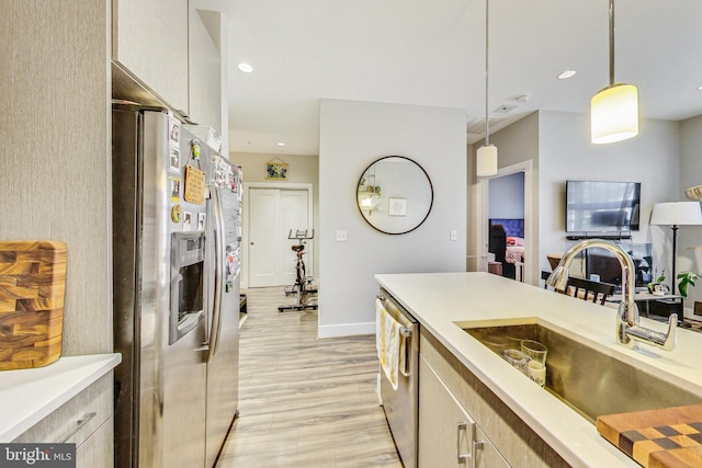 kitchen with appliances with stainless steel finishes, sink, light hardwood / wood-style floors, and hanging light fixtures