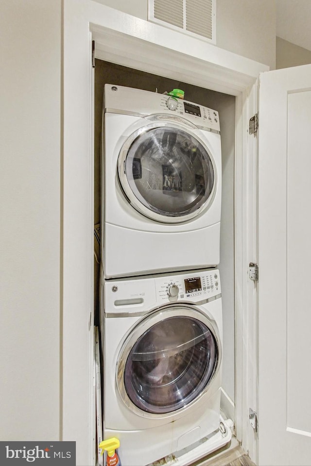 clothes washing area featuring stacked washing maching and dryer