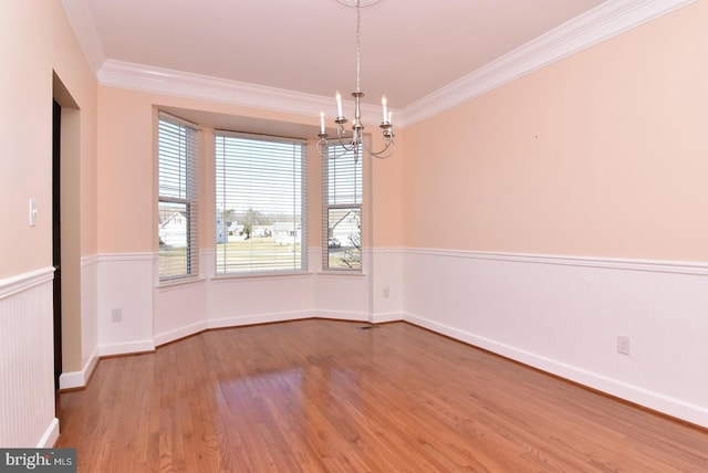 empty room featuring light hardwood / wood-style flooring, crown molding, and a chandelier