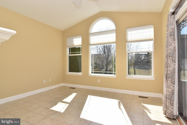 tiled spare room with a healthy amount of sunlight and vaulted ceiling