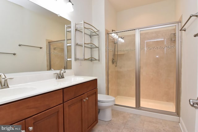 bathroom with tile flooring, double sink vanity, toilet, and a shower with shower door