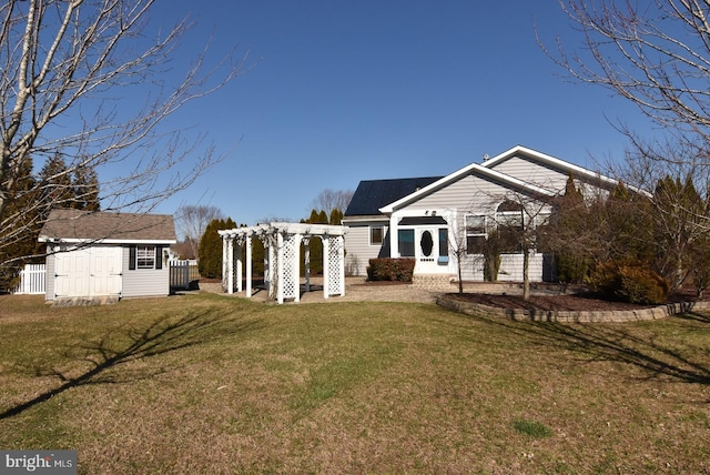 rear view of property featuring a yard, a pergola, and a shed