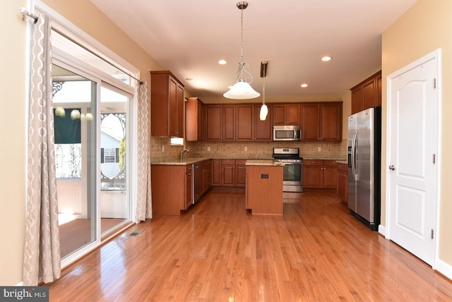 kitchen with plenty of natural light, decorative light fixtures, stainless steel appliances, and a center island