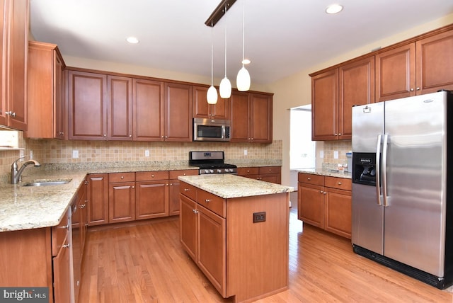 kitchen with pendant lighting, sink, appliances with stainless steel finishes, backsplash, and light wood-type flooring