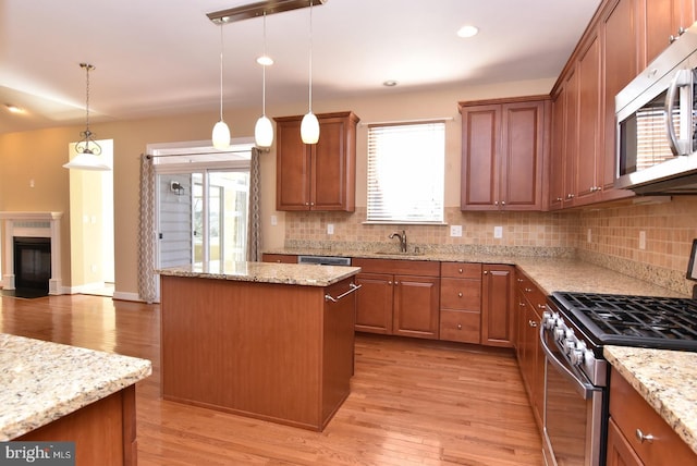 kitchen featuring a center island, hanging light fixtures, stainless steel appliances, and light hardwood / wood-style flooring