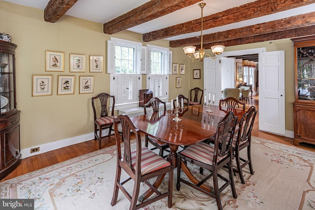 dining area featuring wood-type flooring, beamed ceiling, and a notable chandelier