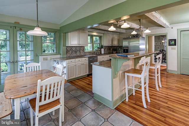 kitchen featuring decorative light fixtures, white cabinets, stainless steel appliances, a kitchen island, and tasteful backsplash