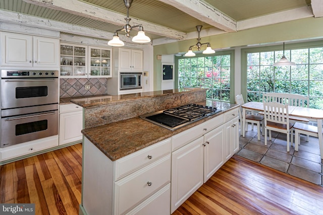 kitchen featuring appliances with stainless steel finishes, beam ceiling, pendant lighting, and backsplash