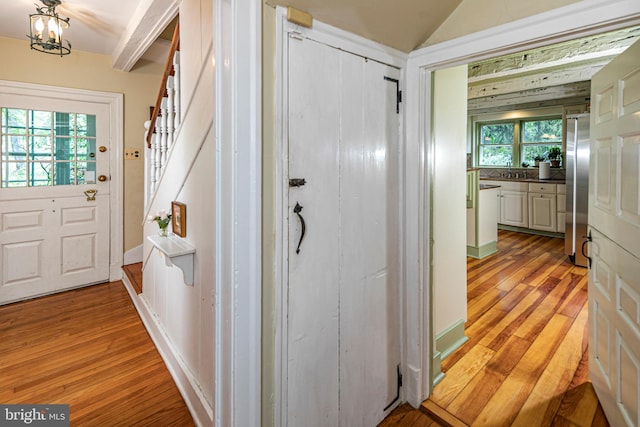 hallway with beamed ceiling, sink, and light hardwood / wood-style flooring