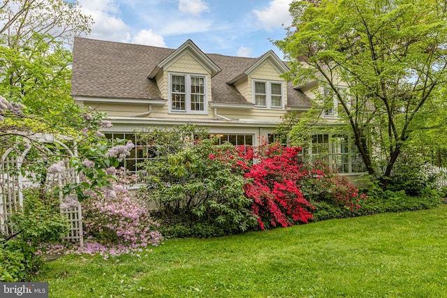 cape cod home featuring a front yard