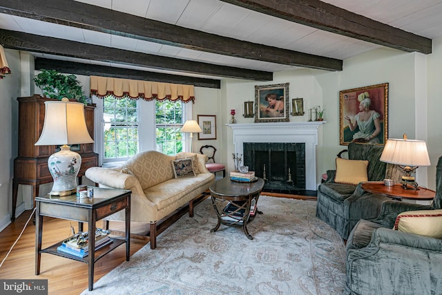 living room featuring beamed ceiling, hardwood / wood-style flooring, and a fireplace