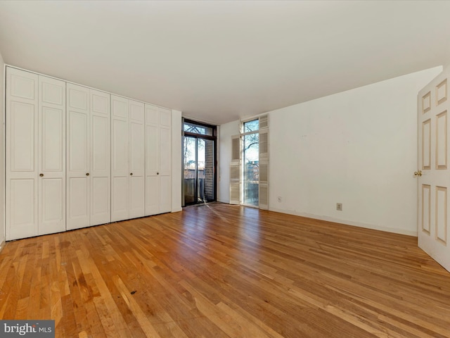 unfurnished bedroom featuring light wood-type flooring and floor to ceiling windows