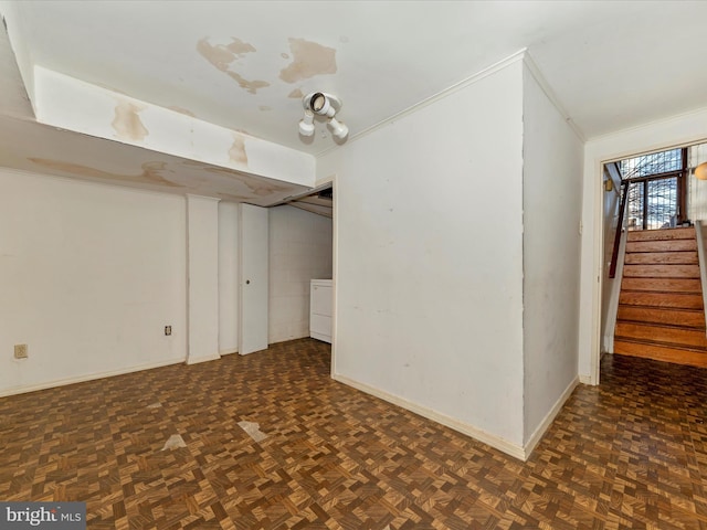 basement featuring crown molding, dark parquet flooring, and washer / dryer