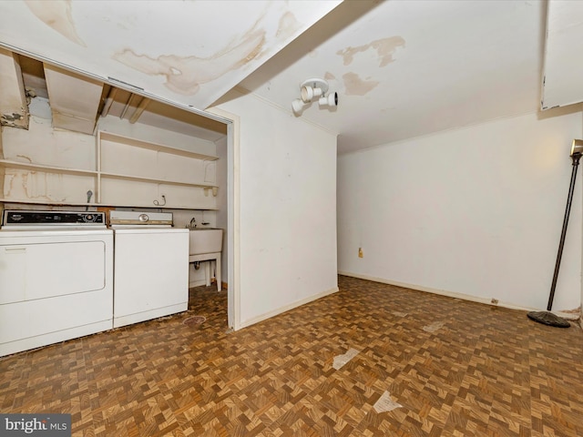 clothes washing area with dark parquet floors, washing machine and dryer, and sink