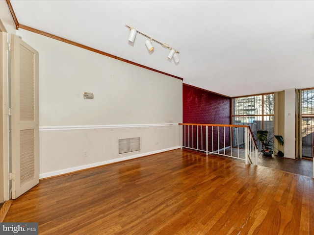 unfurnished living room with hardwood / wood-style flooring, ornamental molding, and rail lighting