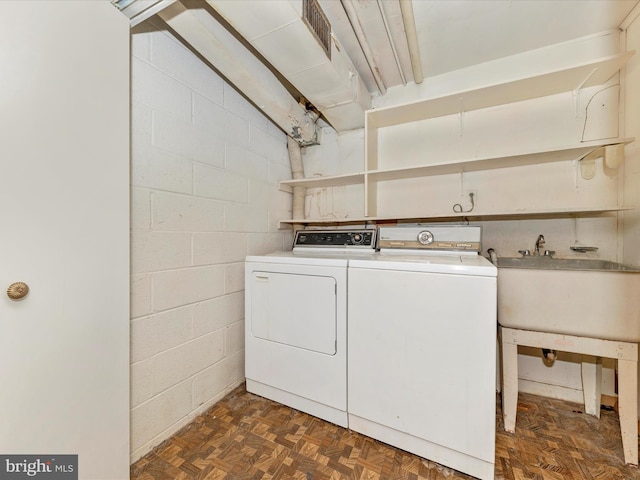 laundry area with washing machine and dryer, dark parquet flooring, and sink