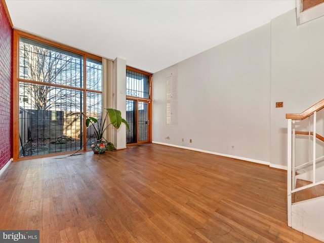 unfurnished living room featuring floor to ceiling windows and wood-type flooring