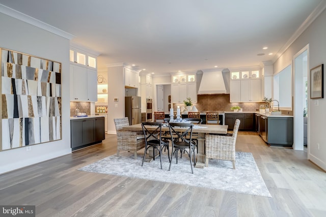 dining room with crown molding, light hardwood / wood-style flooring, and sink