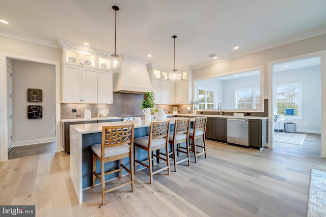 kitchen featuring white cabinetry, custom exhaust hood, stainless steel dishwasher, and a kitchen island