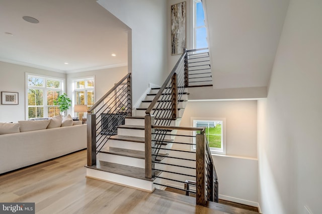 staircase featuring crown molding and light hardwood / wood-style flooring