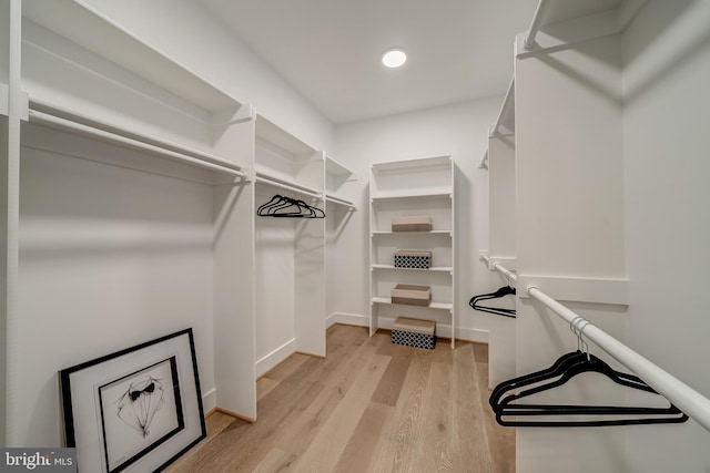 walk in closet with light hardwood / wood-style floors