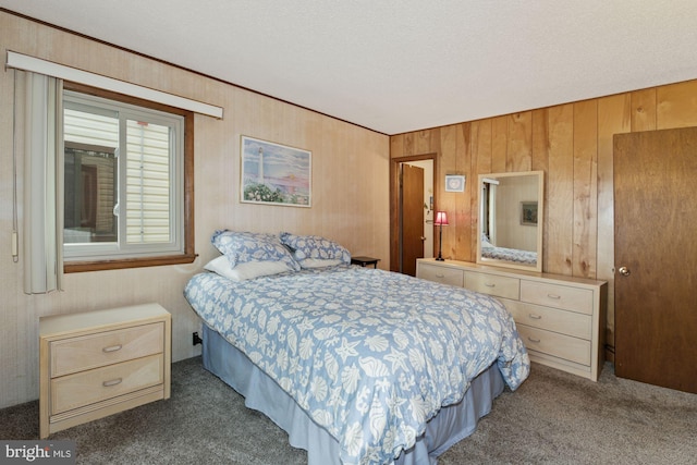 carpeted bedroom with wood walls and a textured ceiling