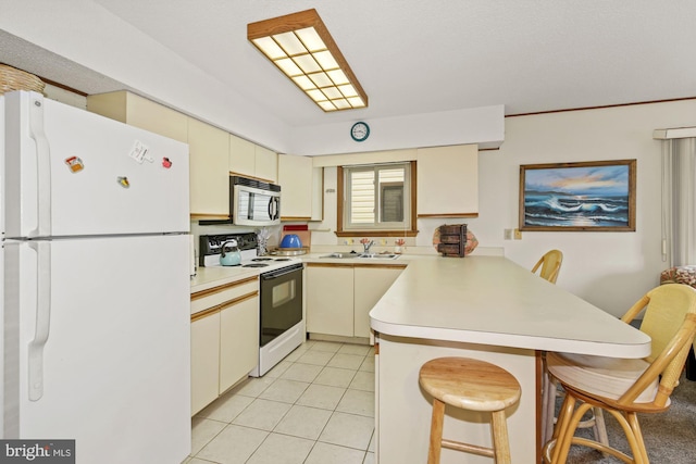 kitchen with light tile floors, a breakfast bar, sink, white appliances, and kitchen peninsula