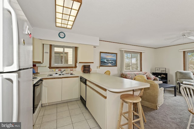 kitchen with ceiling fan, light tile floors, white fridge, kitchen peninsula, and a kitchen breakfast bar