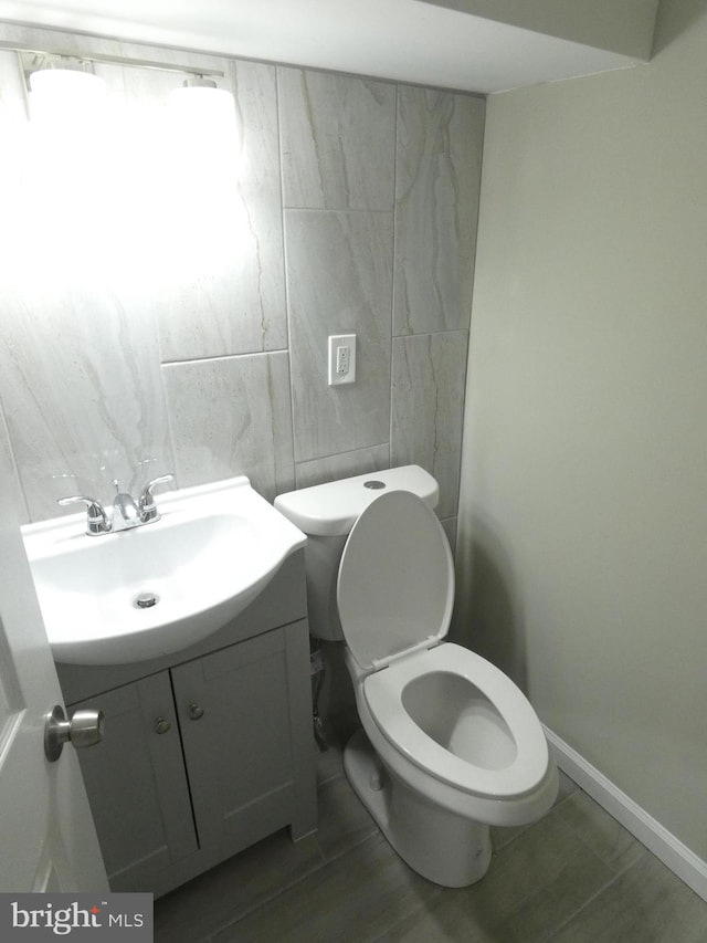 bathroom with vanity, toilet, tile flooring, and tile walls