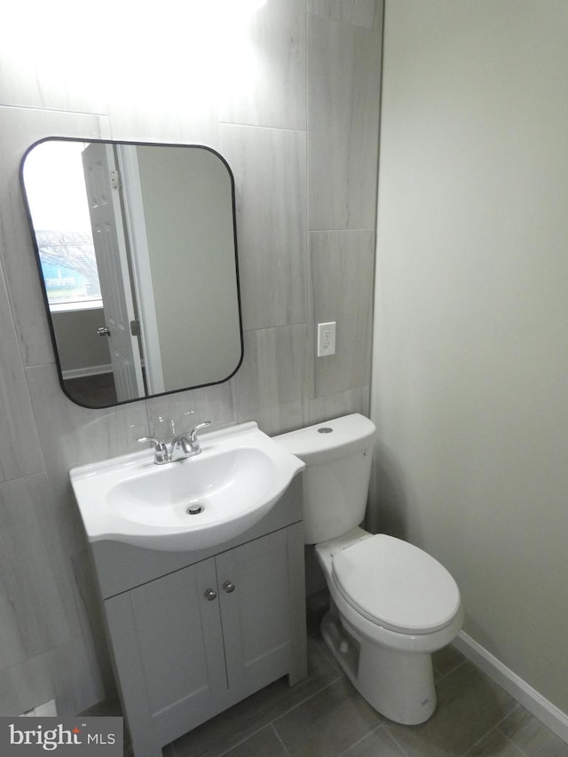 bathroom featuring tile walls, toilet, tile flooring, and vanity