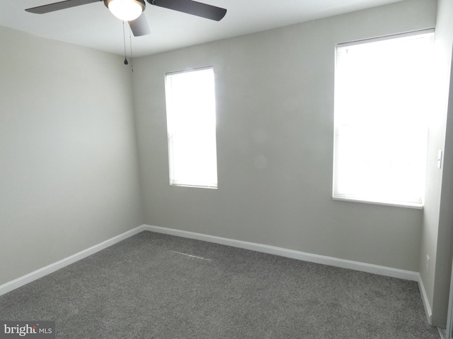 empty room with plenty of natural light, dark carpet, and ceiling fan