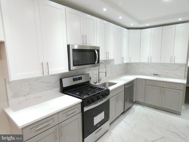 kitchen with stainless steel appliances, tasteful backsplash, white cabinetry, sink, and light tile floors