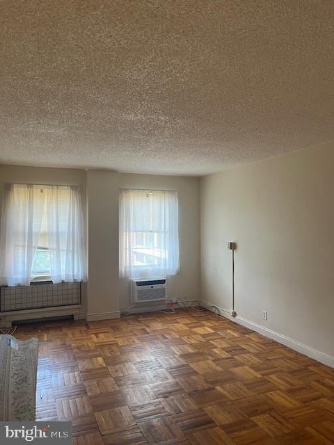 empty room with dark parquet flooring and a textured ceiling