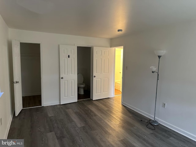 unfurnished bedroom with ensuite bathroom and dark hardwood / wood-style flooring