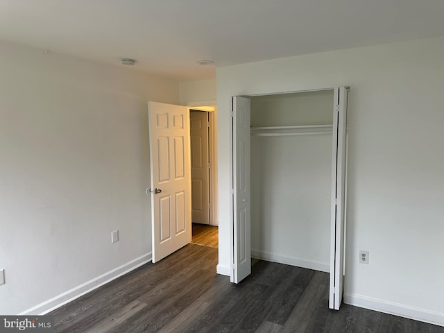 unfurnished bedroom with dark hardwood / wood-style flooring and a closet