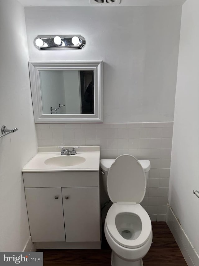 bathroom featuring hardwood / wood-style flooring, vanity, tile walls, and toilet