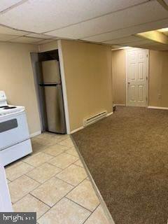 kitchen with a baseboard heating unit, white range with electric stovetop, tile patterned floors, stainless steel fridge, and a paneled ceiling