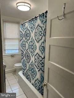 bathroom with tile patterned flooring, shower / tub combo, and toilet