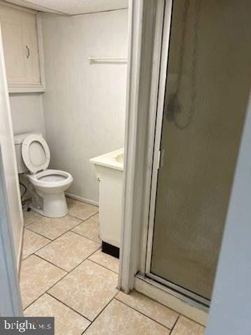 bathroom featuring tile patterned floors, vanity, toilet, and a shower with door